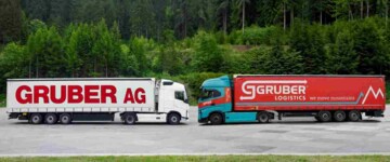 Symbolbild der Übernahme von Gruber AG durch Gruber Logistics im Jahr 2026: Zwei Lkw stehen sich auf einem Parkplatz gegenüber, Links mit Logo und CI der Gruber AG, rechts mit Logo und CI von Gruber Logistics