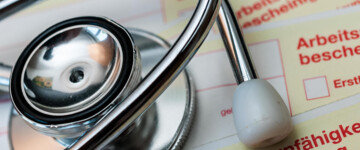 Ein Stethoskop liegt auf mehreren noch unausgefüllten Arbeitsunfähigkeitsbescheinigungen