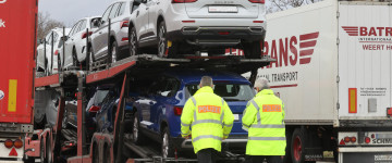 Polizeibeamte kontrollieren einen Lkw, der mit Autos beladen ist