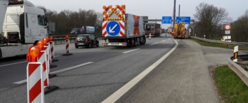 Absperrschilder und -autos blockieren zwei Fahrspuren einer Autobahn, Autos fahren auf der linken Spur vorbei