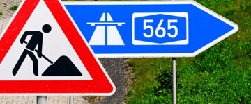 Ausfahrt-Schild einer Autobahn mit Aufschrift A565 und Baustellenschild, Fotomontage 