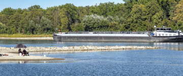 Angler und Tankschiff teilen sich bei extremem Niedrigwasser das Flussbett des Rheins bei Karlsruhe