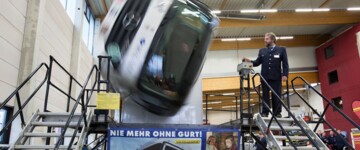 Mann steht neben einem Lkw-Simulator, der sich wild dreht und einen Unfall simuliert
