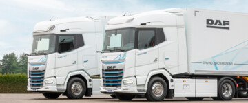 Der neue DAF XG und XG+ Electric parken nebeneinander, die beiden Lkw sind in weiß lackiert und ziehen jeweils einen Kofferauflieger