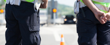 Die Beine von zwei Polizisten bei einer Verkehrskontrolle auf der Autobahn