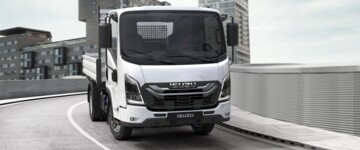 Fahransicht des Isuzu N-Series in urbaner Umgebung. Das weiß lackierte Fahrzeug ist mit einem Kippaufbau ausgerüstet