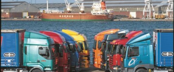 Acht Sattelzugmaschinen parken im Jahr 2000 in Reih und Glied in einem Hafengebiet