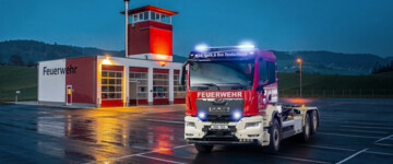MAN-Feuerwehrfahrzeug vor dem Feuerwehrgebäude bei Nacht