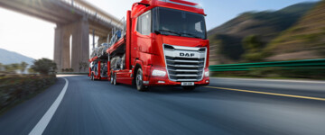Roter DAF XG im Einsatz als Fahrzeugtransporter fährt auf einer Autobahn unter einer Brücke hindurch (grafisches Modell)