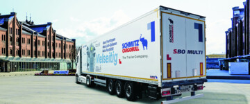 Seitliche Ansicht von hinten des neuen S.BO Multi von Schmitz Cargobull. Der dreiachsige Kofferauflieger steht in einer urbanen Umgebung, eine Sattelzugmaschine ist angehängt