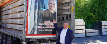 Der bayerische Verkehrsminister Christian Bernreiter vor dem Lkw der Influencerin Christina Scheib, die auf dem Lkw abgebildet ist