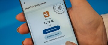 Frauenhand mit Handy mit Digitalem Fahrzeugschein