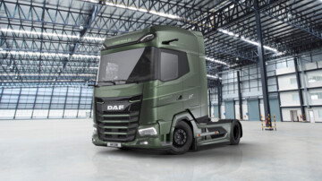 Ansicht des DAF XG+ Emerald Edition von vorn seitlich. Die grün lackierte Sattelzugmaschine parkt in einer Lagerhalle