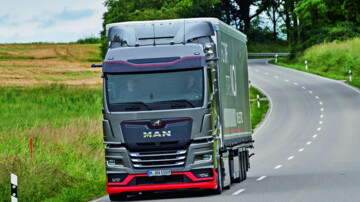 Ein MAN eTGX-Sattelzug fährt über die Landstraße, Rapsfelder im Hintergrund