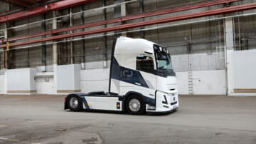 Das neue Sondermodell von Volvo Trucks steht in einer Halle. Die Solo-Sattelzugmaschine ist von vorne rechts fotografiert und präsentiert sich in weißer Lackierung mir schwarzen 100-Jahre-Jubiläums-Schriftzügen  