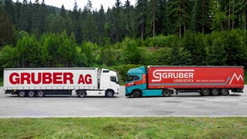 Symbolbild der Übernahme von Gruber AG durch Gruber Logistics im Jahr 2026: Zwei Lkw stehen sich auf einem Parkplatz gegenüber, Links mit Logo und CI der Gruber AG, rechts mit Logo und CI von Gruber Logistics