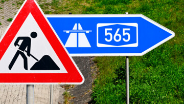 Ausfahrt-Schild einer Autobahn mit Aufschrift A565 und Baustellenschild, Fotomontage 