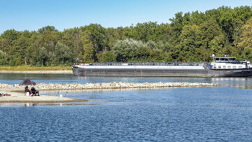 Angler und Tankschiff teilen sich bei extremem Niedrigwasser das Flussbett des Rheins bei Karlsruhe