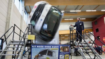 Mann steht neben einem Lkw-Simulator, der sich wild dreht und einen Unfall simuliert