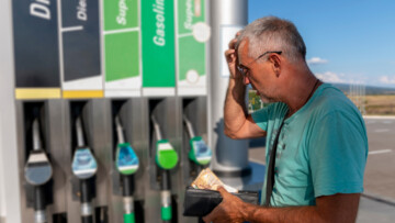 Mann mit Geldbeutel staunt vor Zapfsäule über die Preise