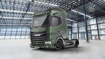 Ansicht des DAF XG+ Emerald Edition von vorn seitlich. Die grün lackierte Sattelzugmaschine parkt in einer Lagerhalle