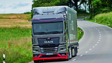 Ein MAN eTGX-Sattelzug fährt über die Landstraße, Rapsfelder im Hintergrund