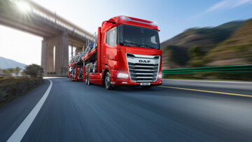 Roter DAF XG im Einsatz als Fahrzeugtransporter fährt auf einer Autobahn unter einer Brücke hindurch (grafisches Modell)