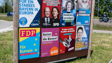 Plakatwand, mehrere Plakate, diverse Parteien. CSU Bayern, Slogan: Fuer ein starkes Bayern in Europa. SPD, Olaf Scholz, Katarina Barley, Slogan: Deutschlands staerkste Stimmen fuer Europa. Die Gruenen, Andrea Woerle, Slogan: Demokratie verteidigen. AFD, Slogan: Zensur verhindern, Europa neu denken. FDP, Slogan: Fuer Europa. Oedp, Slogan: Rettet die Bienen. Die Linke, Slogan: Preise runter, Profite deckeln. Freie Waehler, Christine Singer, Slogan: Ihre Stimme fuer ein Europa der starken Regionen.