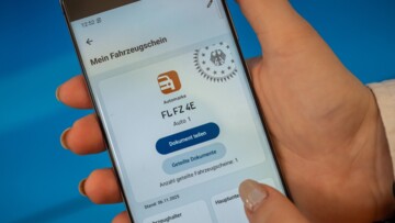Frauenhand mit Handy mit Digitalem Fahrzeugschein
