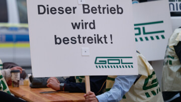 Ein Mann hält ein Schild mit der Aufschrift "Dieser Betrieb wird bestreikt" sowie dem GDL-Logo. (Archivbild vom 12. August 2021) 