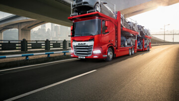 Fahransicht eines DAF XF mit Autotransportaufbau in roter Farbe auf der Autobahn