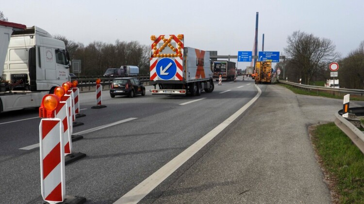 Absperrschilder und -autos blockieren zwei Fahrspuren einer Autobahn, Autos fahren auf der linken Spur vorbei