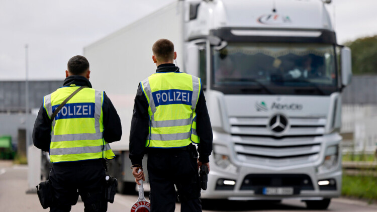 Zwei Polizisten halten einen Lkw zur Kontrolle an