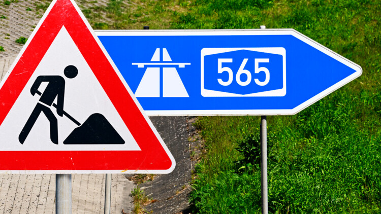 Ausfahrt-Schild einer Autobahn mit Aufschrift A565 und Baustellenschild, Fotomontage 