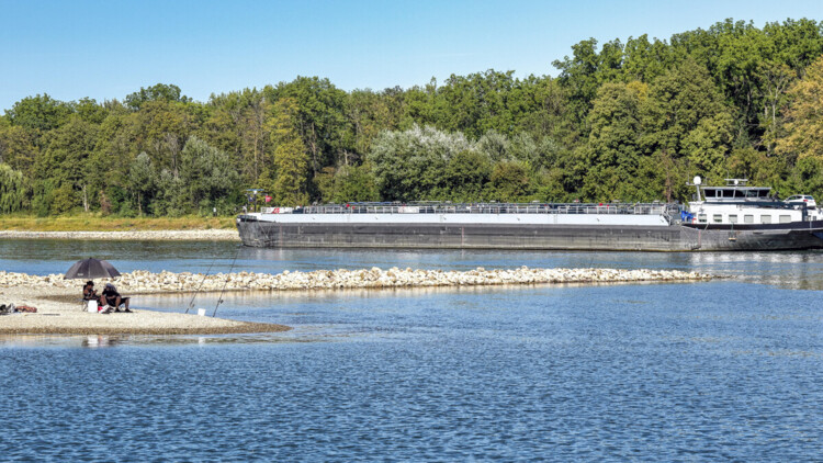 Angler und Tankschiff teilen sich bei extremem Niedrigwasser das Flussbett des Rheins bei Karlsruhe