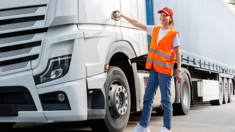 Junge Lkw-Fahrerin in Schutzkleidung an der Tür eines weißen Lkw