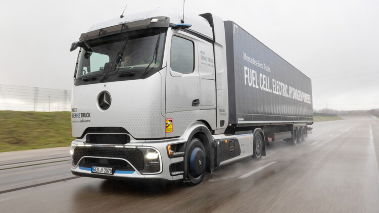 Der Mercedes-Benz NextGenH2 fährt auf einer Teststrecke durch eine Steilkurve. Die silbern lackierte Sattelzugmaschine zieht einen KOfferauflieger