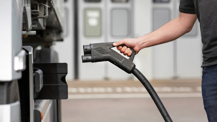 Lkw-Fahrer lädt sein Fahrzeug mit Kabel an einer Ladestation.