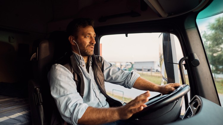 Lkw-Fahrer mit Headset in Fahrerkabine unterwegs