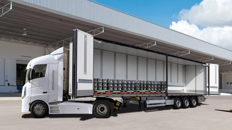 Seitliche Frontansicht der B.BO Obensider von Schmitz Cargobull. Die Seitenwände auf der linken Seite sind geöffnet. Das Fahrzeug parkt auf einem Betriebshof, im Hintergrund sind viele Laderaupen sichtbar