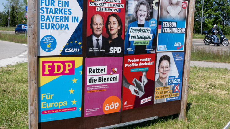 Plakatwand, mehrere Plakate, diverse Parteien. CSU Bayern, Slogan: Fuer ein starkes Bayern in Europa. SPD, Olaf Scholz, Katarina Barley, Slogan: Deutschlands staerkste Stimmen fuer Europa. Die Gruenen, Andrea Woerle, Slogan: Demokratie verteidigen. AFD, Slogan: Zensur verhindern, Europa neu denken. FDP, Slogan: Fuer Europa. Oedp, Slogan: Rettet die Bienen. Die Linke, Slogan: Preise runter, Profite deckeln. Freie Waehler, Christine Singer, Slogan: Ihre Stimme fuer ein Europa der starken Regionen.