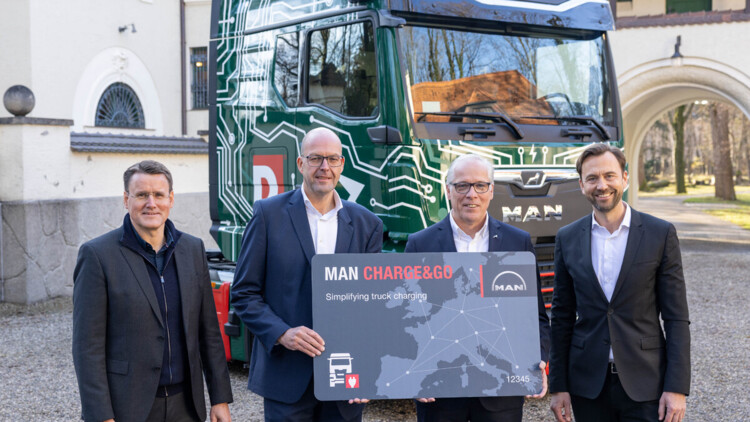 Vor dem MAN eTGX mit Duvenbeck-Unternehmensfarben und Logo stehen mit einer großen grauen Karte, auf der "MAN Charge&Go" zu lesen ist: Alexander Vlaskamp, Vorstandsvorsitzender MAN Truck & Bus, Bernd Reining, Senior Director Procurement, Duvenbeck, Friedrich Baumann, Vorstand Sales & Customer Solutions bei MAN Truck & Bus und Simon Motter, Leiter Volkswagen Konzernlogistik (v.l.n.r.) bei der Übergabe des MAN eTrucks an Duvenbeck