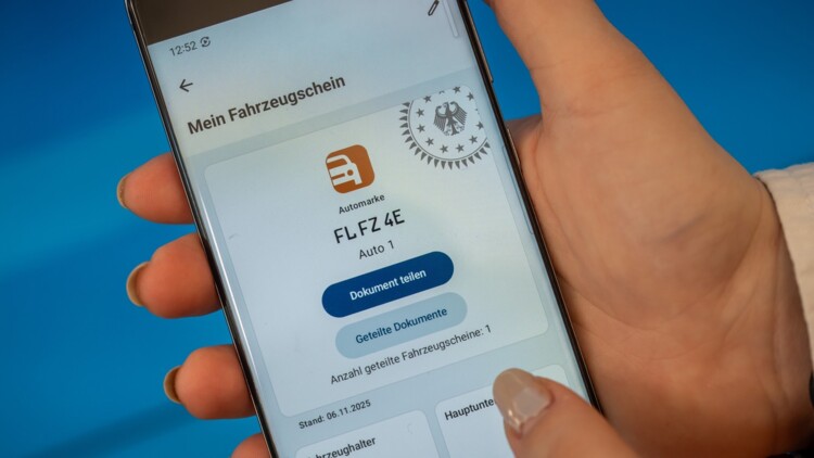 Frauenhand mit Handy mit Digitalem Fahrzeugschein