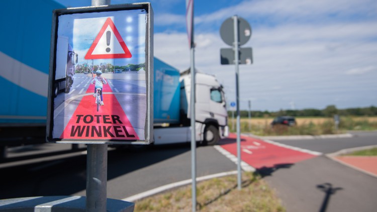 Ein LKW biegt am 23. Juli 2020 an einer Kreuzung rechts ab, während ein Schild mit Aufschrift „Toter Winkel“ eines Schutzsystems hell aufleuchtet und Fahrradfahrer warnt. Zwar schauen Lastwagenfahrer beim Abbiegen in den Spiegel, die Fahrradfahrer im toten Winkel werden aber übersehen. Immer wieder folgen tödliche Unfälle. Das Schutzsystem namens Bike Flash soll Radler vor abbiegenden Lastwagen schützen.