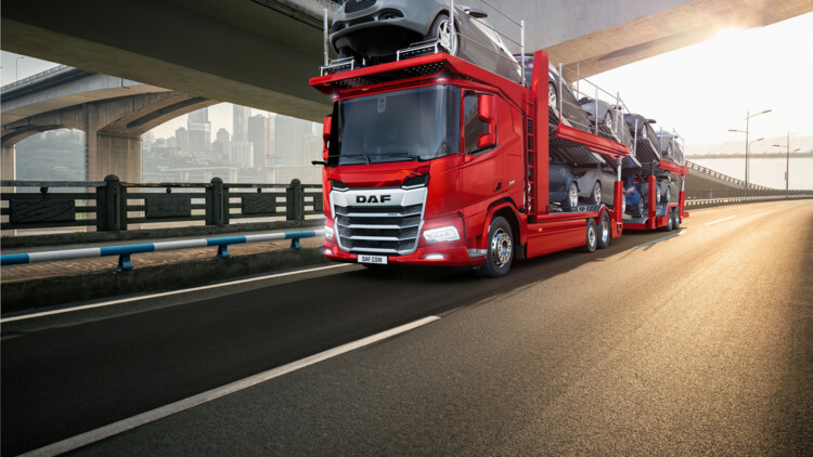 Fahransicht eines DAF XF mit Autotransportaufbau in roter Farbe auf der Autobahn