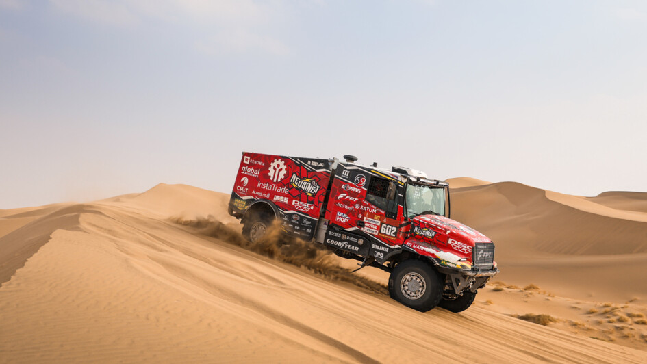 Der rote Iveco-Hauber von Ales Loprais beim Dünensurfen. Im Hintergrund sieht man die unendliche Weite der Wüste 