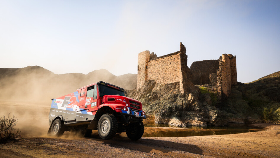 Ein Rallye Truck in rot-schwarzer Lackierung passiert ein verfallenes Schloss